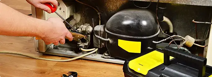 Refrigerator repair technician fixing the compressor and wiring in Olive Branch, MS