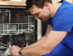 Dishwasher repair technician inspecting and servicing an open dishwasher in Memphis, TN