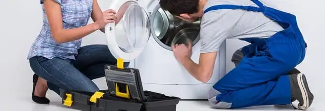 Washer repair technician inspecting a front-load washing machine with tools in Memphis, TN
