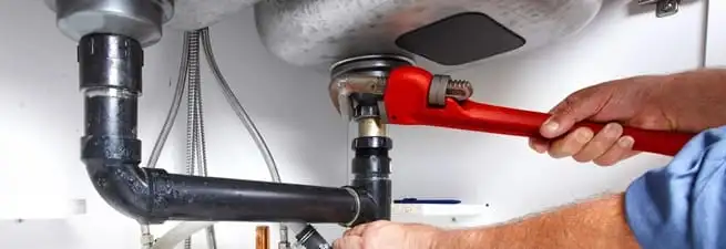 Garbage disposal repair technician tightening the sink drain and disposal connection in Memphis, TN