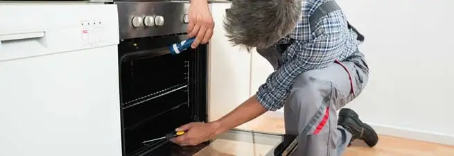 Oven repair technician inspecting and servicing an electric oven in Memphis, TN