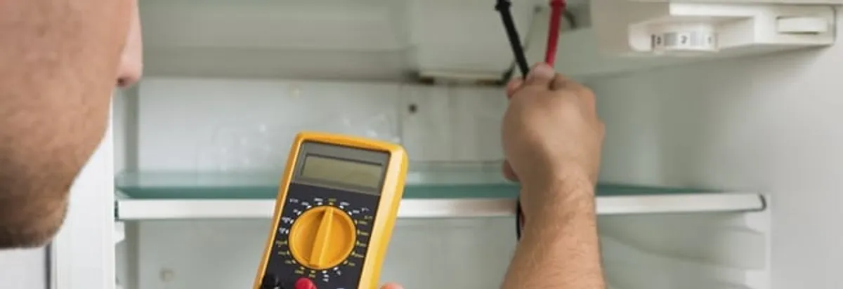 Refrigerator repair technician testing electrical components with a multimeter in Memphis, TN