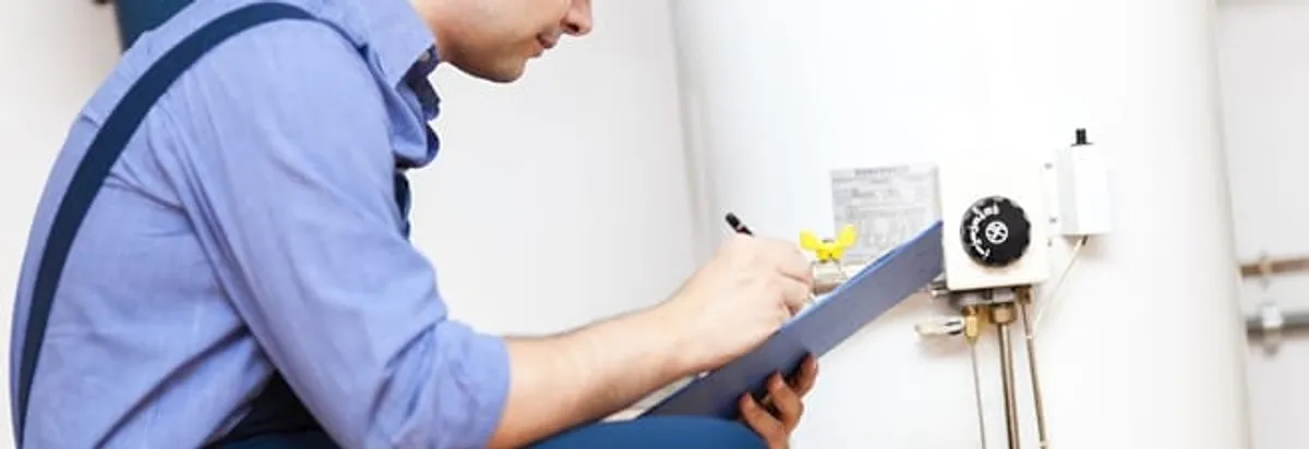 Water heater repair technician inspecting the unit and recording service notes in Memphis, TN