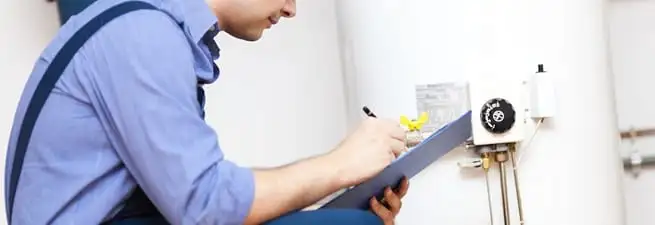 Water heater repair technician inspecting the unit and recording service notes in Memphis, TN